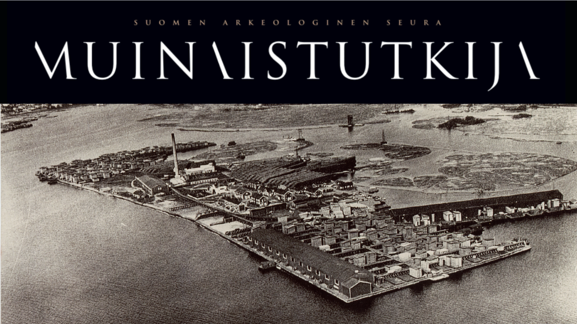 Laitakarin saha vuonna 1935. Ilmakuva, saari on rakennettu suorakaiteen muotoiseksi ja se on täynnä puisia rakennuksia, talon korkuisia lautakasoja sekä sahan rakennuksia tehtaanpiippuineen.